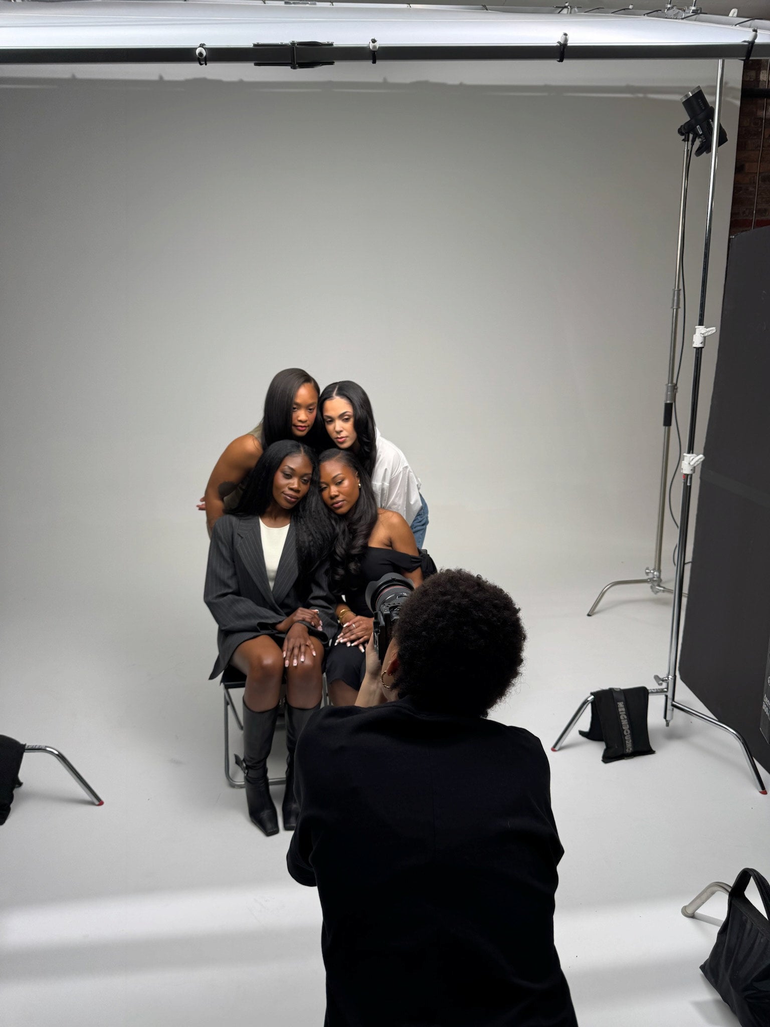 Backstage photo of a photographer taking a group photo with models in a studio setting.