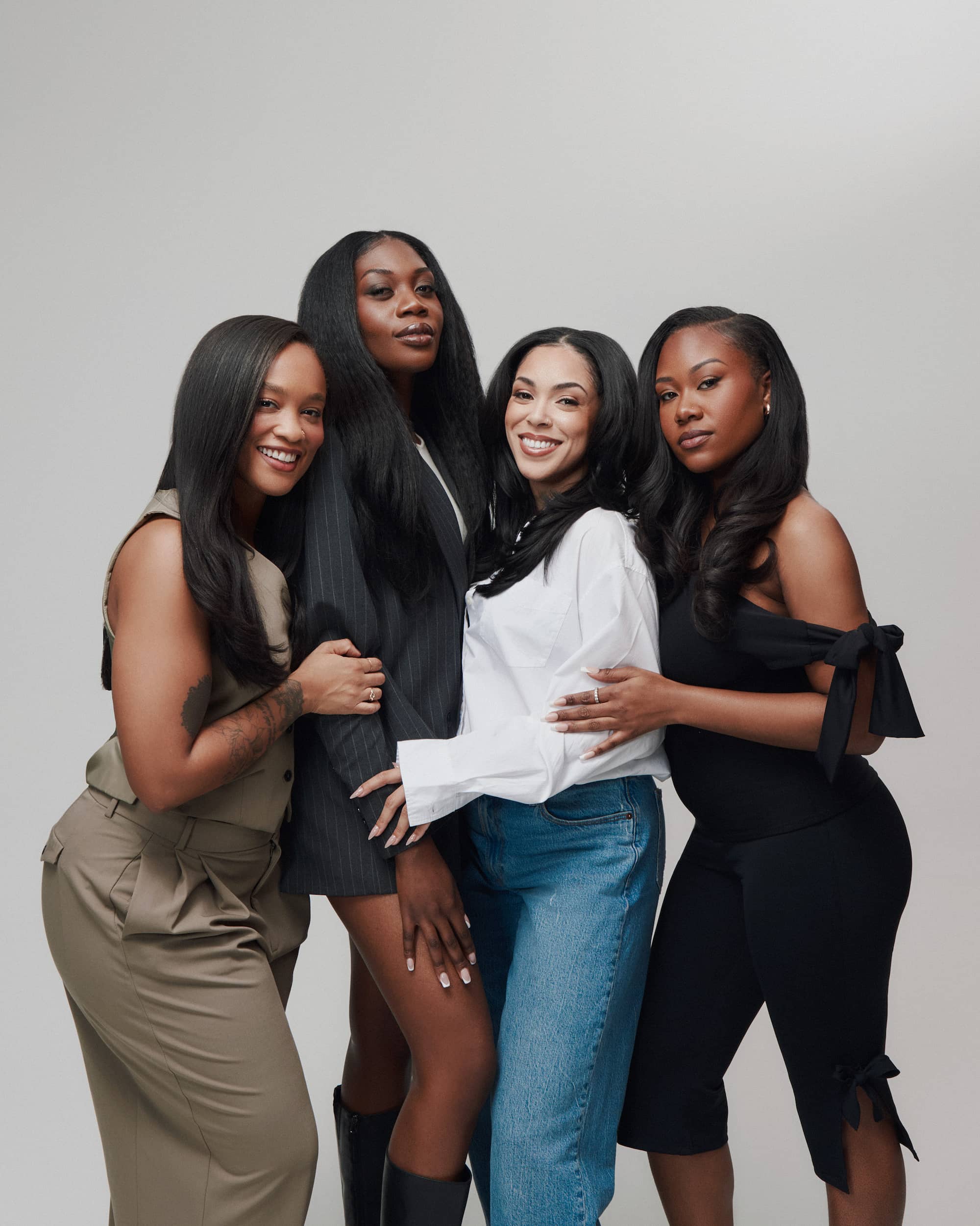Four women with long, styled hair posing together against a neutral background